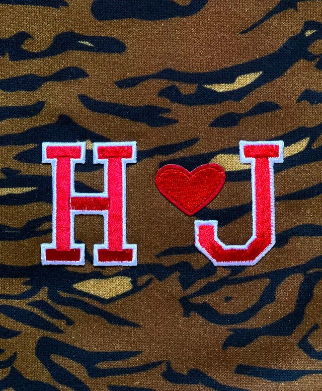 Dettaglio del ricamo a forma di cuore racchiuso tra le lettere ‘H’ e ‘J’, simbolo di amore e inclusività, sulla nostra shopping bag genderless con stampa tigrata