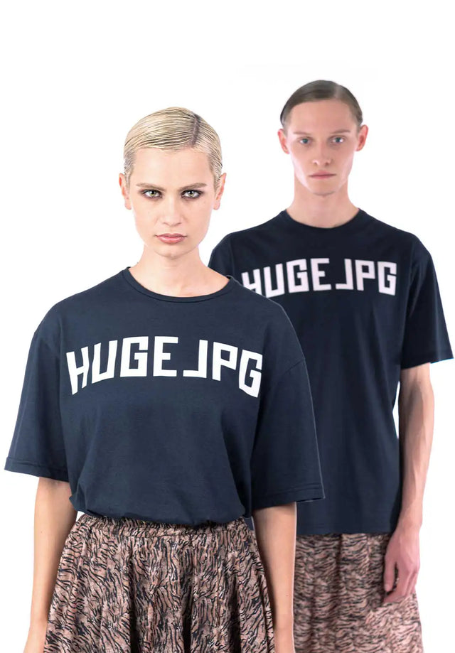 Ragazzo e ragazza indossano maglietta oversize nera con logo bianco di Huge Jpg, illustrando l'uso genderless del capo.